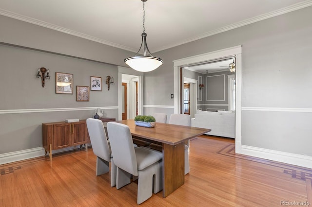 dining area featuring light wood-type flooring, crown molding, and baseboards