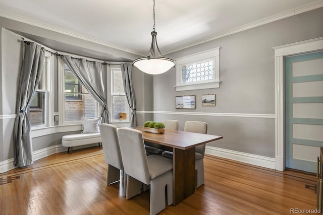 dining room with wood finished floors, baseboards, and ornamental molding