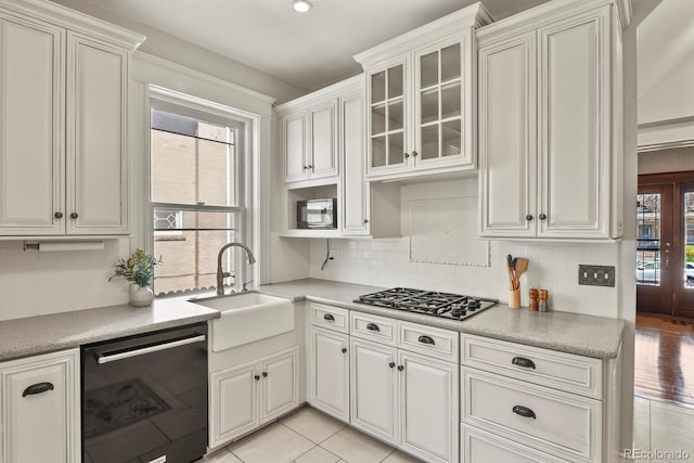 kitchen with a sink, light countertops, decorative backsplash, and black appliances