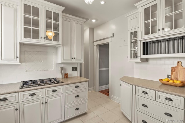 kitchen featuring baseboards, light countertops, decorative backsplash, stainless steel gas cooktop, and light tile patterned flooring
