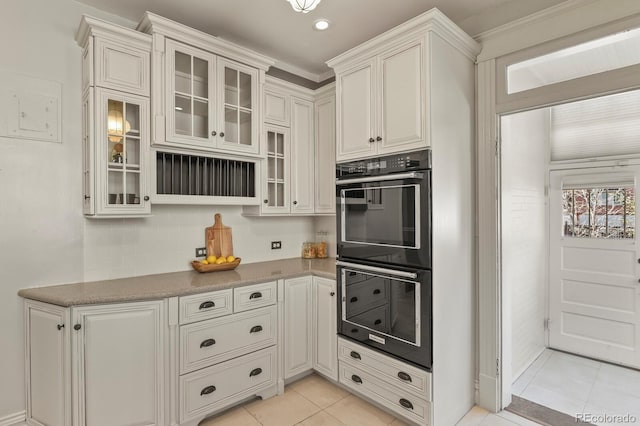 kitchen featuring dobule oven black, light tile patterned floors, glass insert cabinets, white cabinetry, and recessed lighting