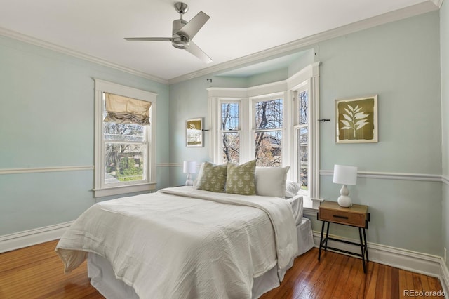 bedroom with a ceiling fan, wood finished floors, baseboards, and ornamental molding