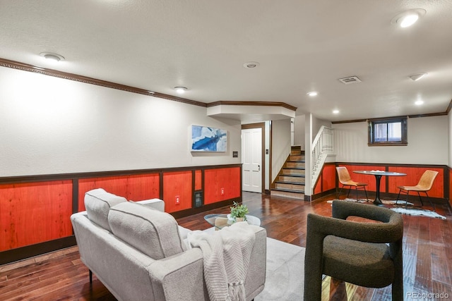 living room featuring baseboards, crown molding, stairs, visible vents, and wood-type flooring