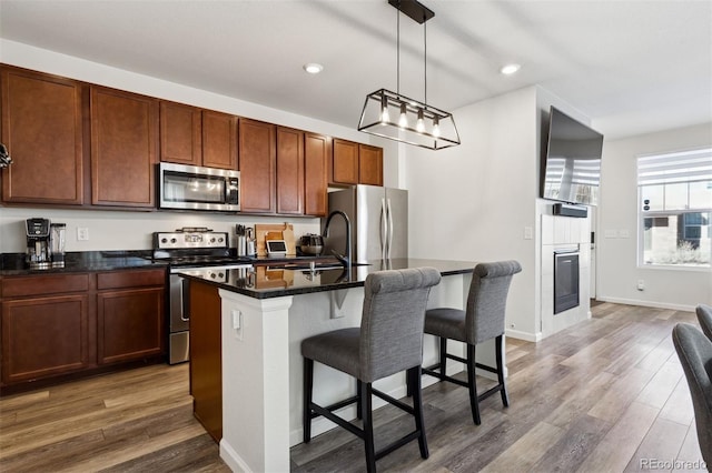 kitchen featuring sink, hanging light fixtures, dark hardwood / wood-style floors, an island with sink, and appliances with stainless steel finishes