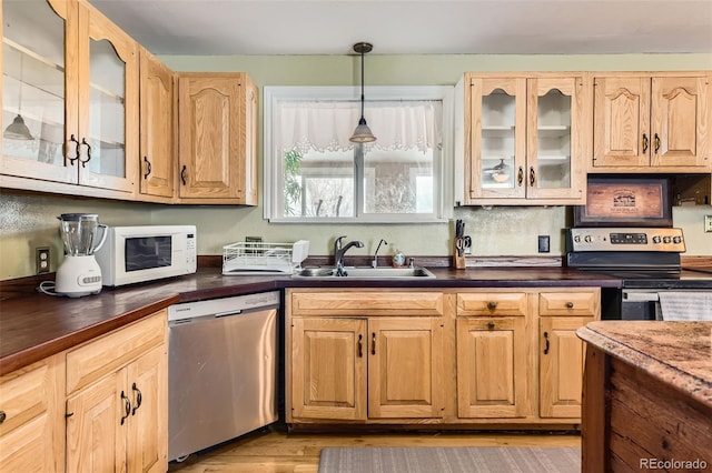 kitchen featuring appliances with stainless steel finishes, sink, light brown cabinetry, and decorative light fixtures