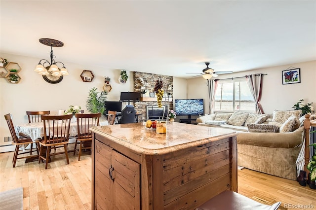 kitchen featuring ceiling fan with notable chandelier, light hardwood / wood-style floors, and a center island