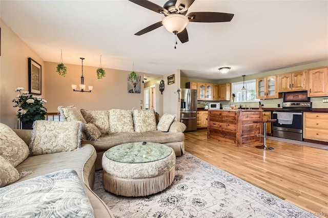 living room featuring sink, ceiling fan with notable chandelier, and light hardwood / wood-style floors