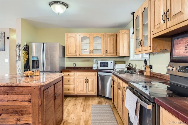 kitchen with stainless steel appliances, sink, light brown cabinets, and light wood-type flooring