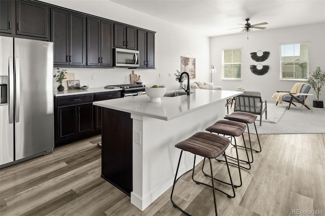 12547 Lake View St, Longmont, CO 80504 - kitchen with appliances with stainless steel finishes, a sink, a kitchen breakfast bar, light countertops, and a center island with sink