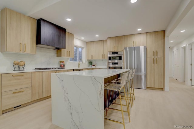 kitchen featuring a breakfast bar area, a center island, light brown cabinets, and appliances with stainless steel finishes