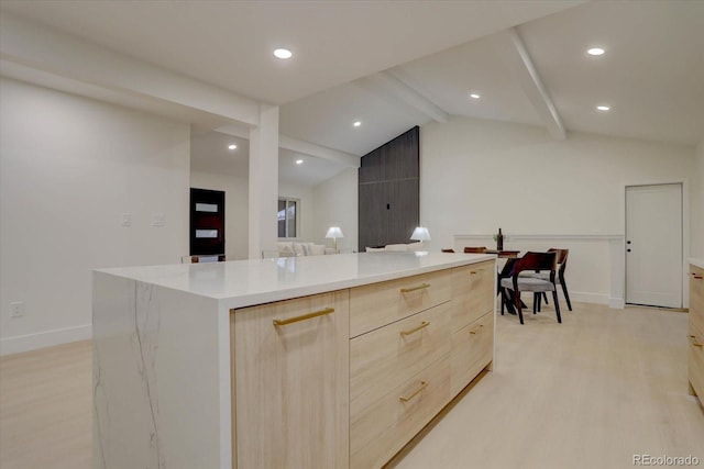 kitchen featuring lofted ceiling with beams, a kitchen island, light hardwood / wood-style floors, and light brown cabinets