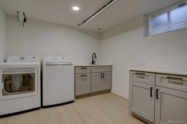 laundry area featuring cabinets, sink, washer and dryer, and light hardwood / wood-style floors