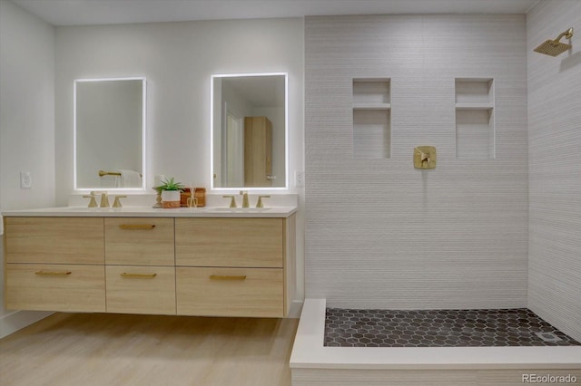 bathroom featuring a tile shower, vanity, and wood-type flooring