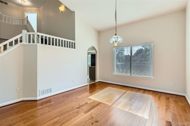 12701 Elm Ln, Broomfield, CO 80020 - spare room with wood finished floors, a chandelier, arched walkways, and vaulted ceiling