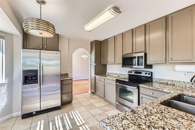 12701 Elm Ln, Broomfield, CO 80020 - kitchen featuring stainless steel appliances, arched walkways, light tile patterned floors, and light stone countertops