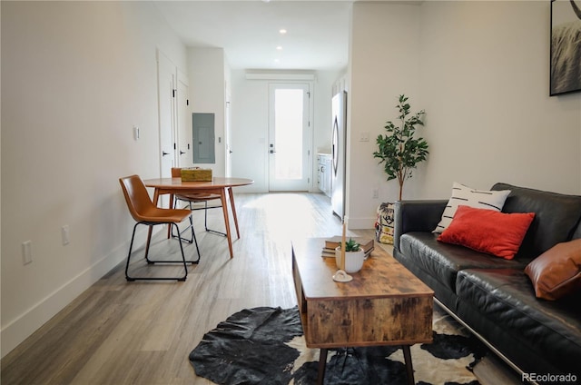 living room featuring light wood finished floors, electric panel, baseboards, and recessed lighting