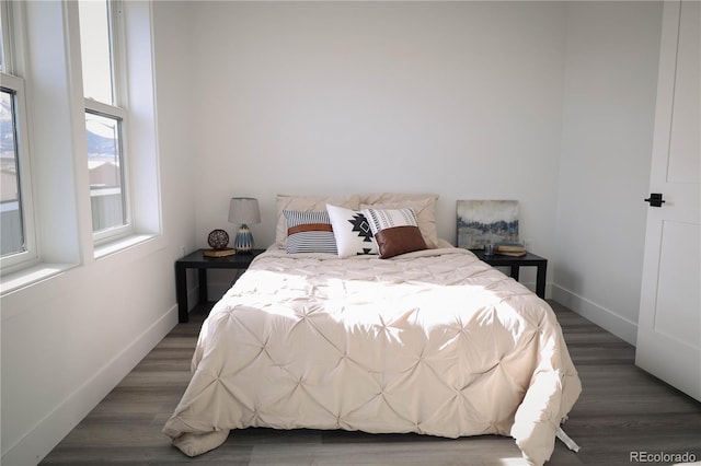 bedroom with baseboards and dark wood-type flooring