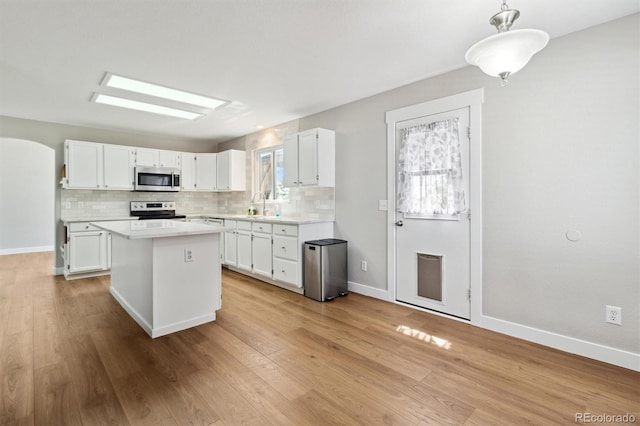 1462 Marigold Dr, Lafayette, CO 80026 - kitchen featuring appliances with stainless steel finishes, a sink, a kitchen island, light countertops, and white cabinets