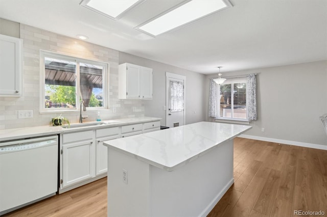 1462 Marigold Dr, Lafayette, CO 80026 - kitchen with dishwasher, a sink, light wood-style floors, white cabinets, and decorative backsplash