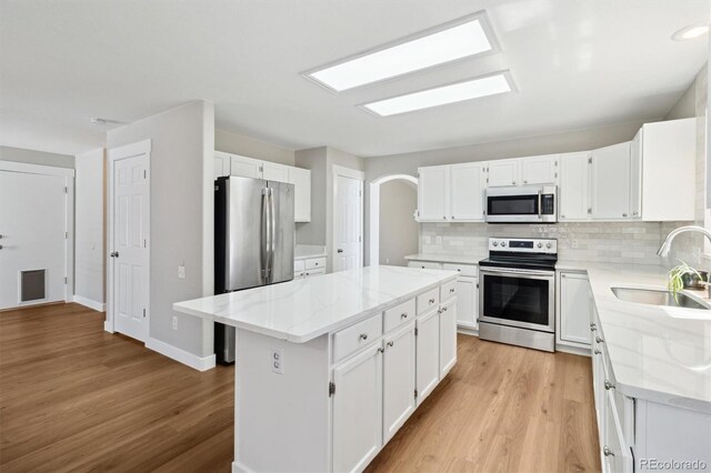 1462 Marigold Dr, Lafayette, CO 80026 - kitchen with appliances with stainless steel finishes, a sink, a center island, light wood-style floors, and decorative backsplash