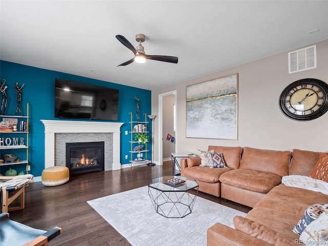 living room with a fireplace, dark wood-type flooring, and ceiling fan