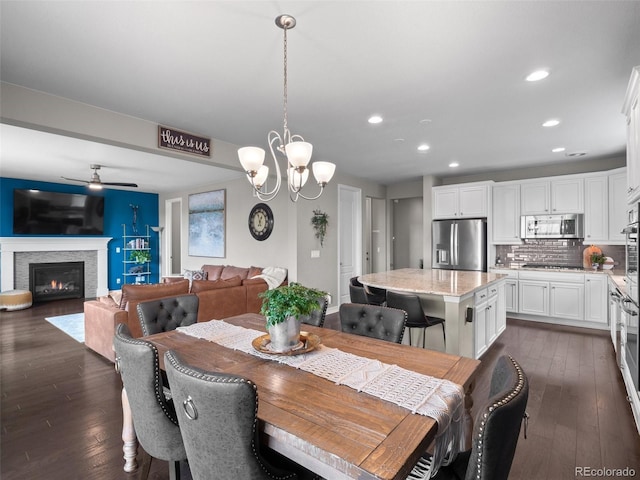 dining area with dark hardwood / wood-style floors and ceiling fan with notable chandelier