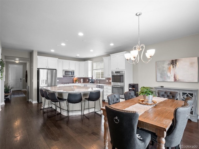 dining space with a notable chandelier, sink, and dark wood-type flooring