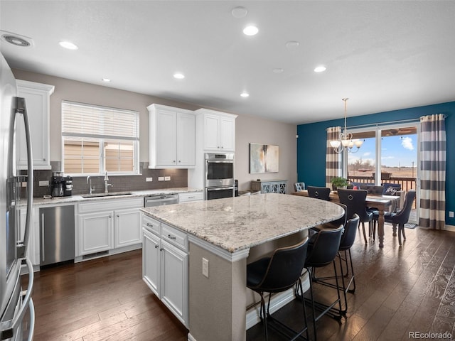 kitchen with a kitchen island, sink, hanging light fixtures, and white cabinetry