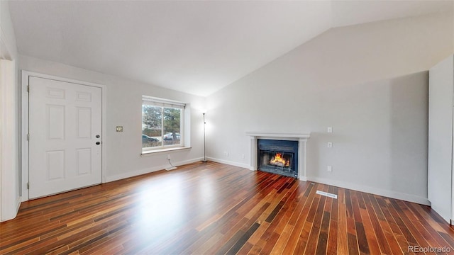 unfurnished living room with lofted ceiling, baseboards, wood finished floors, and a glass covered fireplace