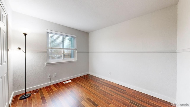 unfurnished bedroom featuring baseboards, visible vents, and wood finished floors