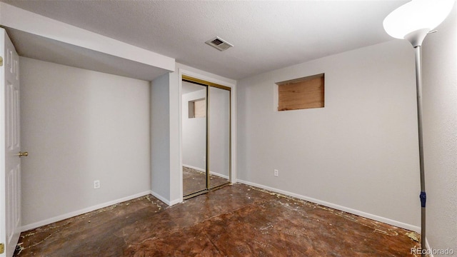 unfurnished bedroom featuring concrete flooring, visible vents, a textured ceiling, and baseboards