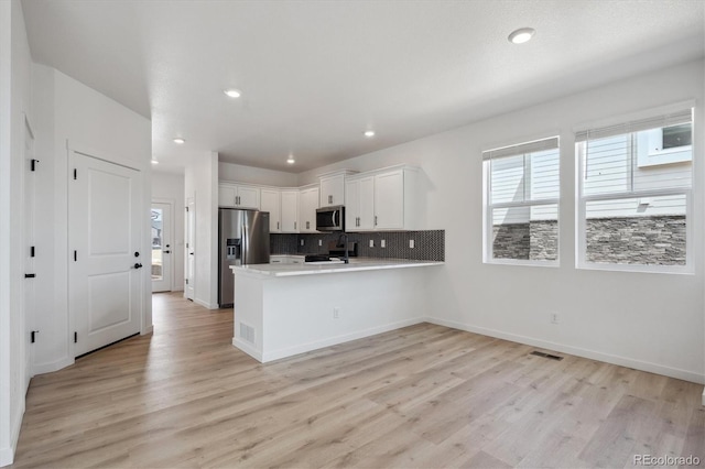22363 E 6th Pl, Aurora, CO 80018 - kitchen featuring appliances with stainless steel finishes, light wood-type flooring, a peninsula, white cabinetry, and light countertops