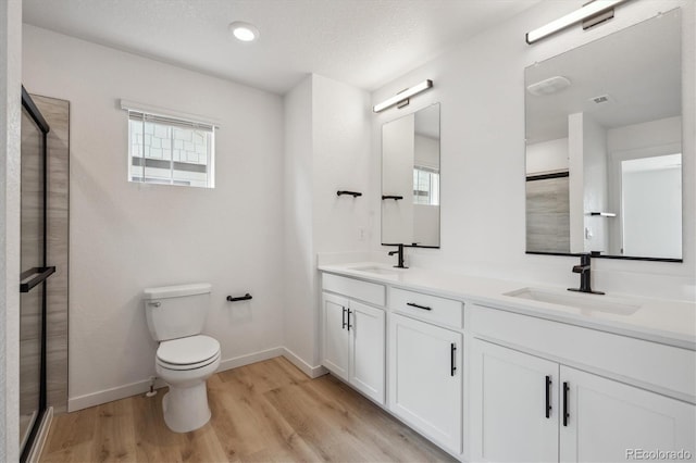 22363 E 6th Pl, Aurora, CO 80018 - full bathroom featuring wood finished floors, double vanity, baseboards, toilet, and a shower stall
