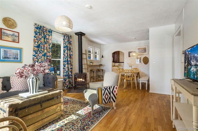 living room with a wood stove, wood finished floors, and arched walkways