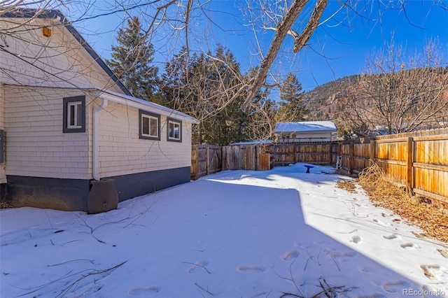 yard covered in snow with a fenced backyard and a mountain view