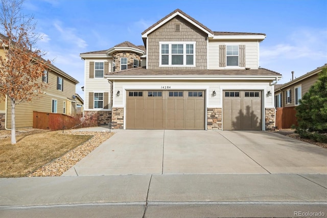 craftsman inspired home featuring stone siding, driveway, an attached garage, and fence