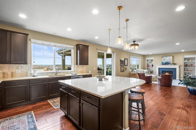 kitchen featuring a breakfast bar, a healthy amount of sunlight, dark wood-style floors, and a sink