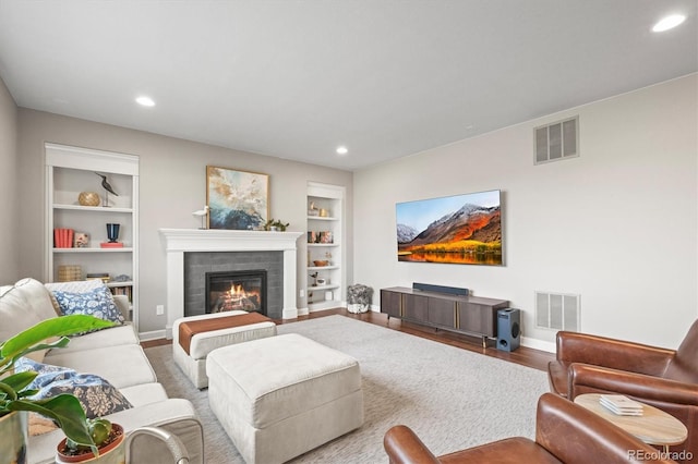 living room with built in shelves, recessed lighting, and visible vents