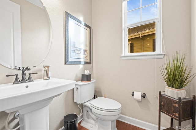 bathroom featuring a sink, toilet, baseboards, and wood finished floors