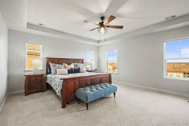 carpeted bedroom featuring visible vents, baseboards, and a tray ceiling