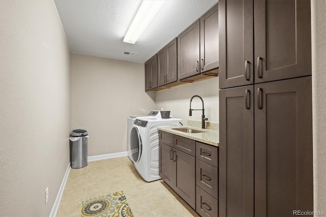 clothes washing area with visible vents, a sink, washing machine and dryer, cabinet space, and baseboards