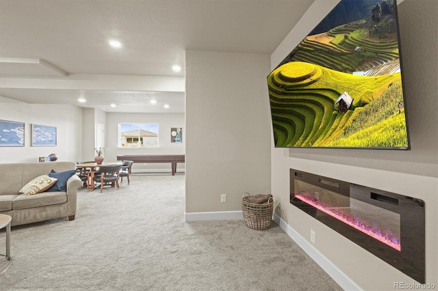 living area featuring a glass covered fireplace, recessed lighting, baseboards, and carpet floors