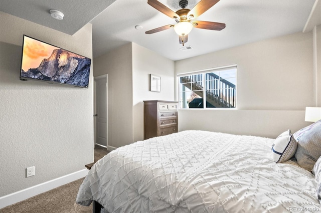 bedroom featuring visible vents, baseboards, ceiling fan, dark carpet, and a textured wall