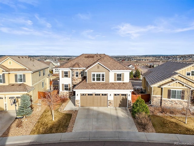 view of front facade with fence, concrete driveway, a garage, stone siding, and a residential view