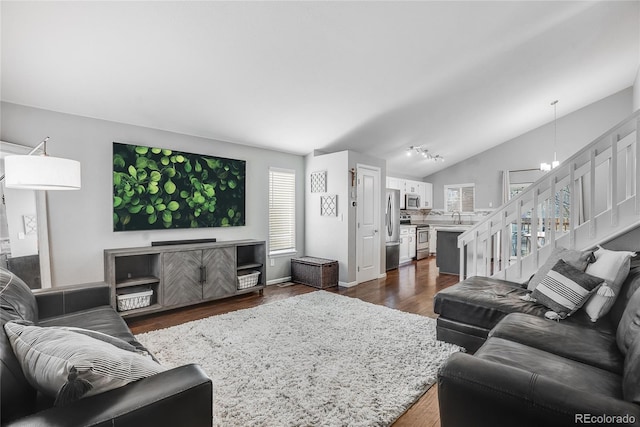 living room featuring vaulted ceiling, dark hardwood / wood-style floors, sink, and a chandelier