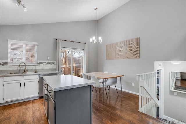 kitchen with sink, vaulted ceiling, a kitchen island, pendant lighting, and white cabinets