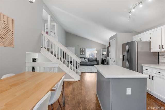 kitchen featuring dark wood-type flooring, lofted ceiling, a breakfast bar, white cabinetry, and stainless steel fridge