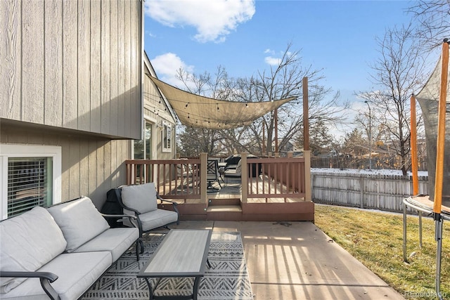 wooden terrace featuring an outdoor hangout area, a trampoline, and a lawn