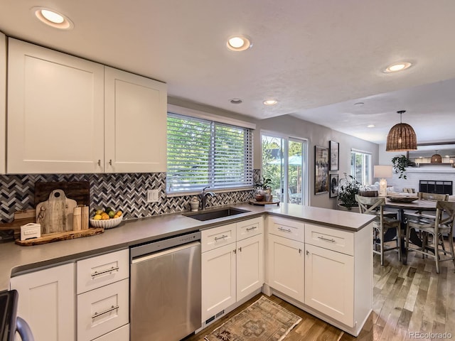4196 S Reading Way, Denver, CO 80237 - kitchen with stainless steel dishwasher, a sink, a peninsula, decorative backsplash, and white cabinets
