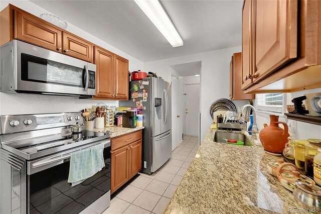 4848 S Pitkin Way, Aurora, CO 80015 - kitchen featuring stainless steel appliances, a sink, light tile patterned floors, and brown cabinetry